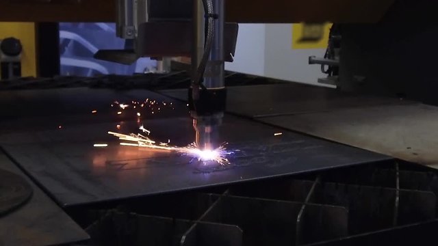 Automatic CNC plasma cutting machine cuts details from steel sheet.