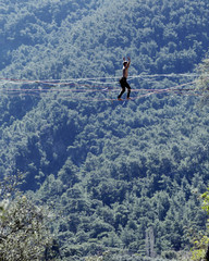 Highliner on a rope. Highline on a background of mountains. Extreme sport on the nature. Balancing on the sling. Equilibrium at altitude.