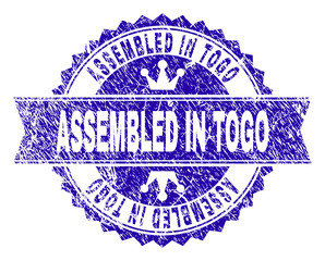 Obraz premium ASSEMBLED IN TOGO rosette stamp imitation with grunge style. Designed with round rosette, ribbon and small crowns. Blue vector rubber print of ASSEMBLED IN TOGO caption with grunge style.