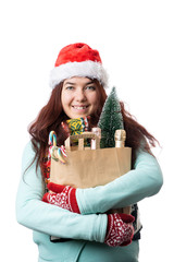 Photo of woman in Santa's cap with paper bag with artificial Christmas tree, champagne