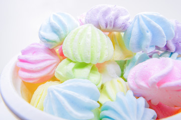 Close up colorful meringues in plastic cup isolated on white background.