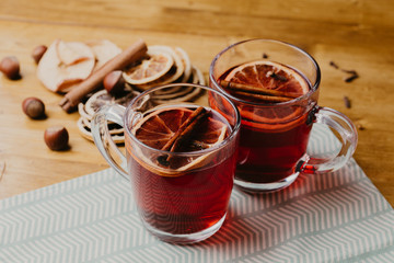 Mulled wine in mugs with scarf on wooden table.