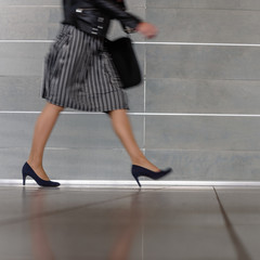 Closeup of elegant busy woman walking on gray background