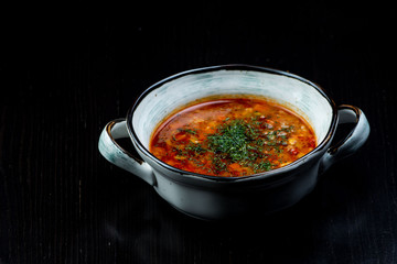 Vegetable soup with red beans, borscht, tomato soup, soup kharcho in a white plate on a black background
