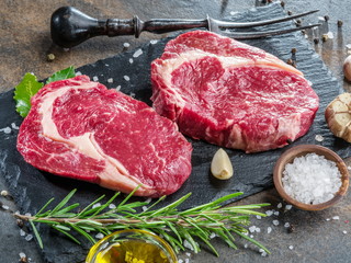 Raw  Rib eye steak or beef steak on the graphite board with herbs and spices.