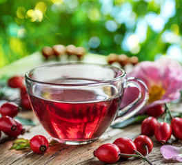 Rose-hips and rose hip seed oil on the wooden table.
