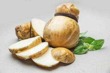 Traditional Italian smoked Scamorza cheese with herbs on gray background. © volff