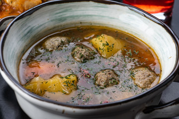 Soup with meat meatballs, potatoes and vegetables. in a white plate on a black background