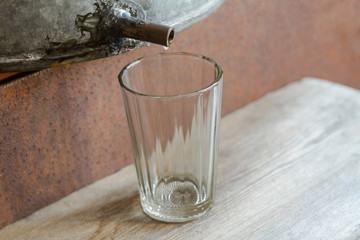 Moonshining. Manufacture of moonshine at home. Moonshine is dripping into the glass. Closeup, selective focus