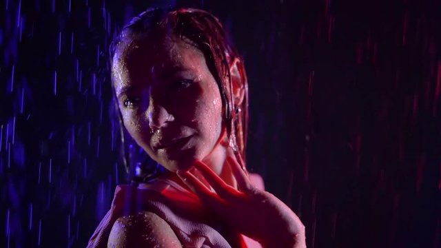 beautiful girl is dancing under rain in night, her hair and face are wt, she is moving her hands
