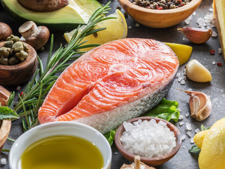 Raw salmon with spices and vegetables on the graphite board.