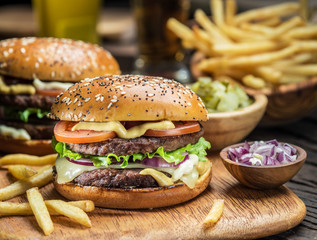 Hamburgers and French fries on the wooden tray.