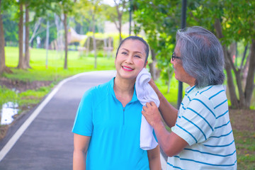 They are happy Asian couple. Man is rub the face woman after Jogging in park.They smile and be happy in good time,this photo relates about a husband,wife,love Photo concept Health and relax time.