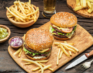 Hamburgers and French fries on the wooden tray.