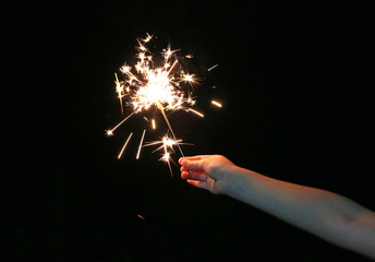 Close-up child hand holding fire sparklers on the dark at festival. © zilvergolf