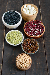 Healthy food, dieting, nutrition concept, vegan protein source. Assortment of colorful raw legumes: green peas, beans, chickpeas in bowls, on a wooden table.