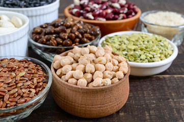 Healthy food dieting nutrition concept, vegan protein and carbohydrate source. Assortment of colorful raw legumes in bowls on a wooden table.