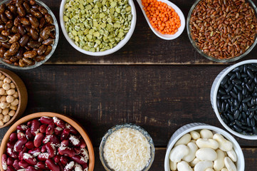 Healthy food, dieting, nutrition concept, vegan protein and carbohydrate source. Assortment of colorful raw legumes in bowls on a wooden table. Top view, flat lay background
