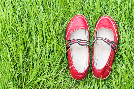 pair of red shoes on green grass copy space