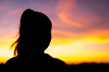 Silhouette woman standing sad in the sunset.