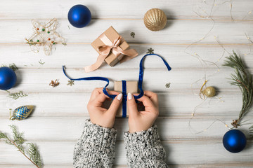 A woman holding a Christmas gift with a ribbon on a wooden table. Christmas presents and New Year