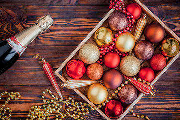 Wooden box filled with Christmas decorations on wooden background. Christmas or new year preparations. . Flat lay various Christmas toys in a box, top view.