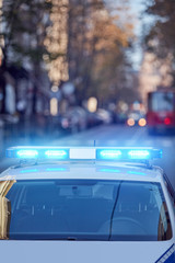 Obraz na płótnie Canvas Police car with blue lights on the crime scene in traffic / urban environment.