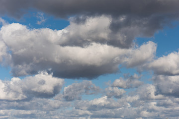 Obraz premium Beautiful white and grey fluffy clouds soar over a deep blue background. Cloudscape with autumn dark storm clouds moving fast over blue sky day.