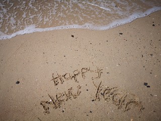 Fototapeta na wymiar Happy New Year written on the beach