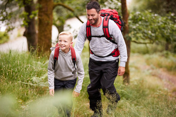 Pre-teen boy and his father hiking in a forest, selective focus