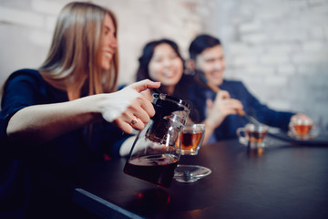 Defocused photo. Girl takes guests house, pouring tea and smiling broadly. Concept of home gatherings, meeting