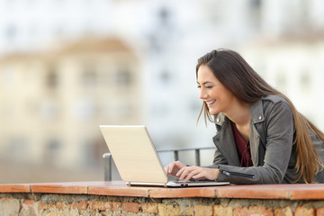 Happy woman using a laptop in a terrace