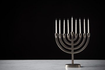 Metal Hanukkah Menorah With Unlit Candles On Marble Surface Against Black Studio Background