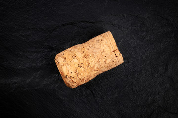 An overhead closeup photo of a champagne cork on a dark background with copy space