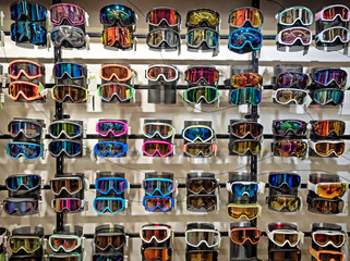 Sport equipment background. Colored snowboard masks in a rows on a showcase. Colorful ski masks on the shop window in the sports shop.