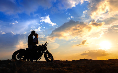 Couple in love silhouettes with motorbike  at sunset sky