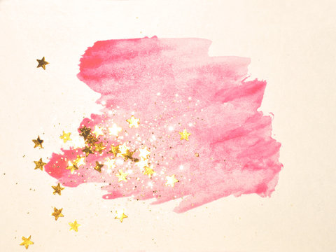 Golden glitter and glittering stars on abstract pink watercolor splash in vintage nostalgic colors.