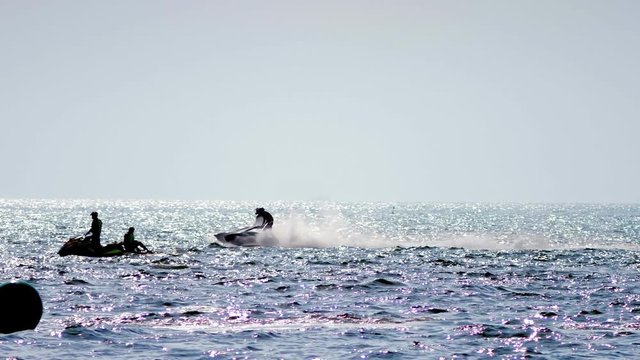 silhouette, a men on a motorbike floats on the sea.