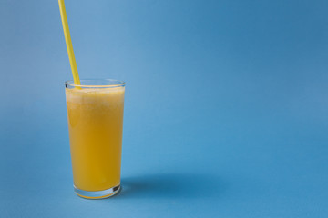 A glass of pineapple fruit juice over blue colorful background.