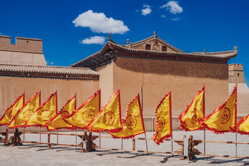Red and yellow flags in front of traditional Chinese buildings at Jiayu Pass, in Jiayuguan, China