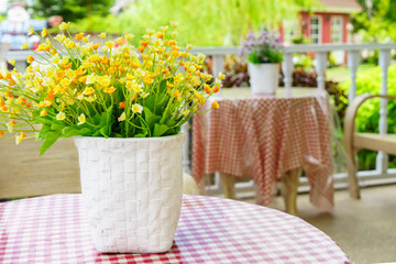 Artificial flowers and vase on table. They are on a porch for decoration.