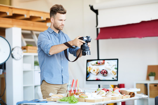 Portrait of handsome photographer taking photos of food while working in studio, copy space