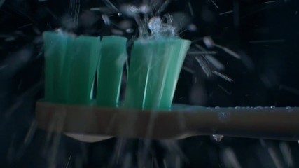 Drops of water fall into electric toothbrush and splatter on black background. - Powered by Adobe