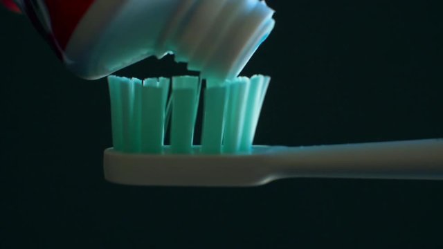 Squeezing toothpaste from tube onto toothbrush