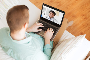 medicine, technology and healthcare concept - close up of man or patient having video call with male doctor on laptop computer at home