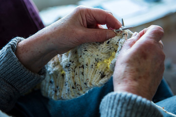 Close up of an older womens hands knitting a jumper