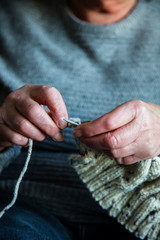 Close up of an older womens hands knitting a jumper
