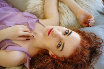 Obraz na płótnie Canvas beautiful young woman with red hair lying on the couch