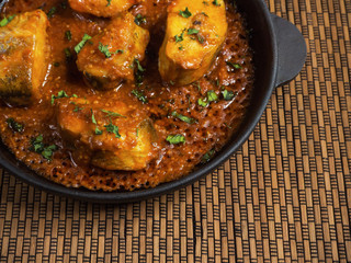 Top view of spicy and hot Bengali fish curry. Indian food. Fish curry with red chili, curry leaf, coconut milk. Asian cuisine.