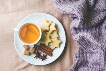 Cup of tea with lemon and cookies, honey and cinnamon sticks, star anise on the blanket.. Christmas, winter concept.